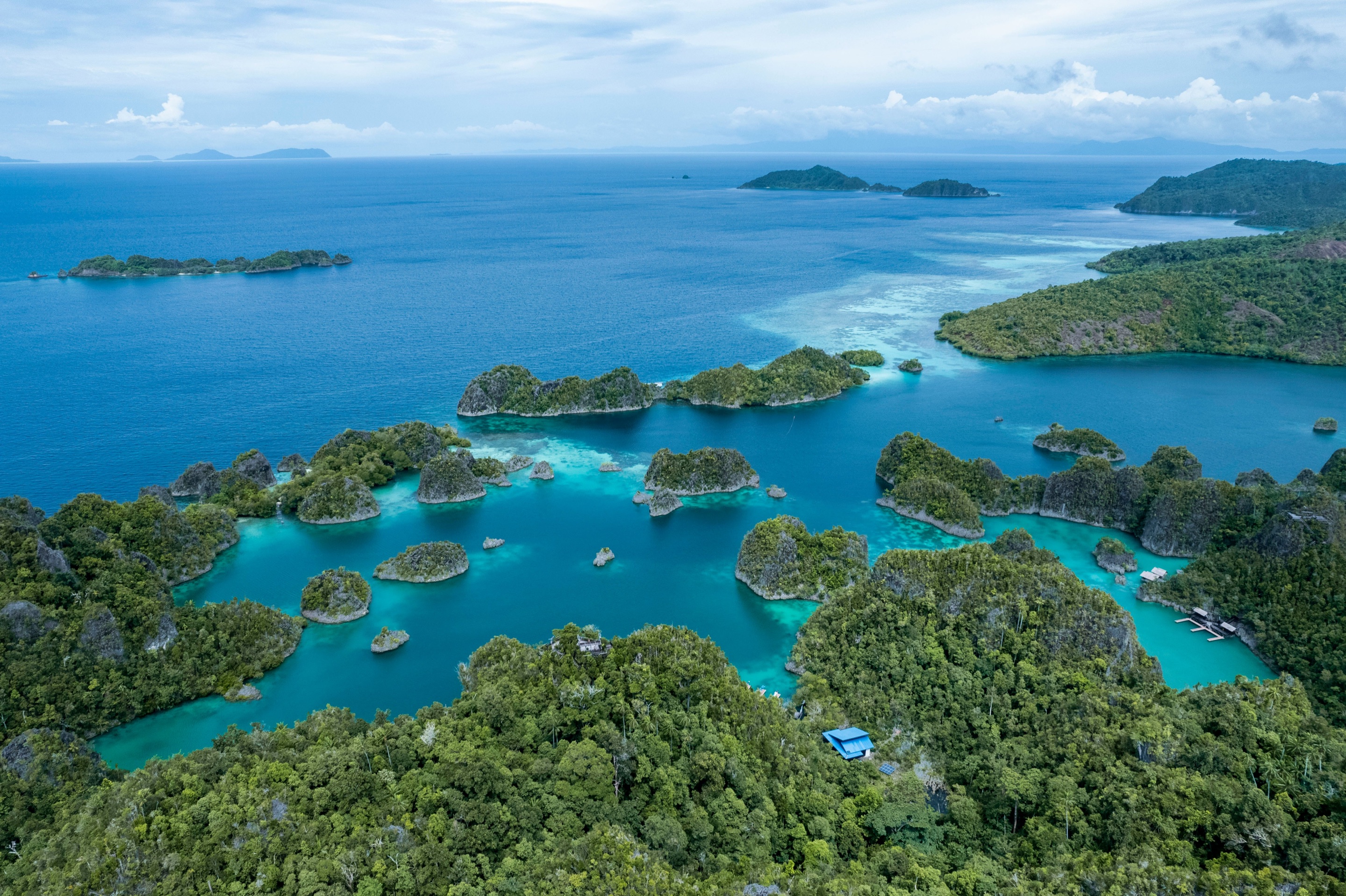 Aerial view from the Pyanemo viewpoint in Raja Ampat, with jungle-covered karst islets and turquoise lagoons